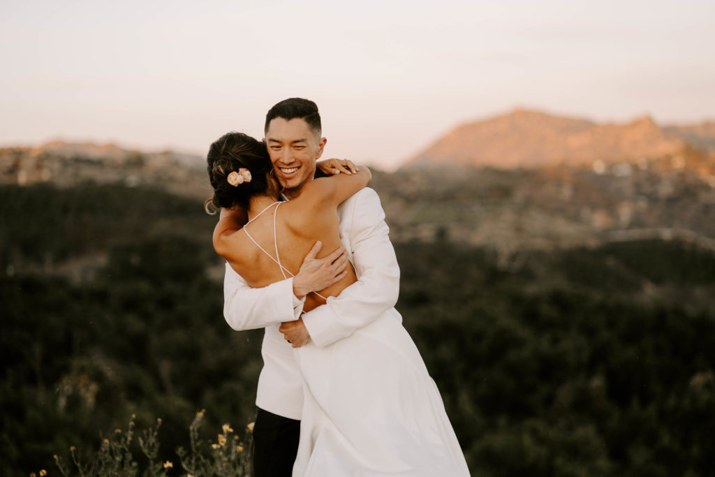 Photo of newly wed couple hugging with a mountain in the background
