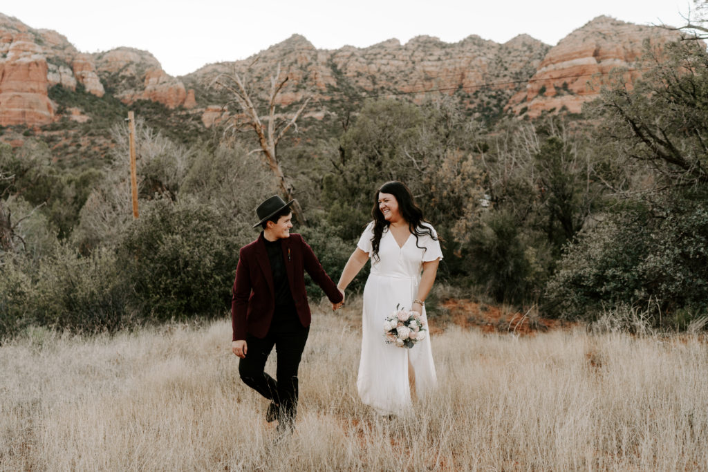 Photo of a newly wed couple walking in front of mountains and greenery