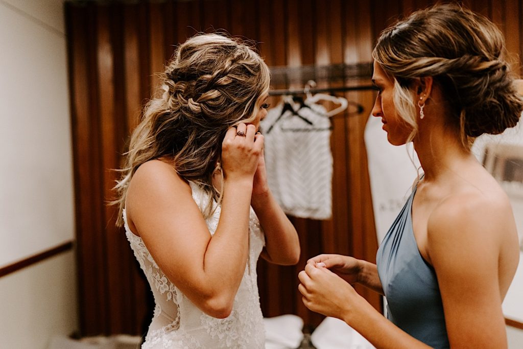 Bride putting on earrings on wedding day 