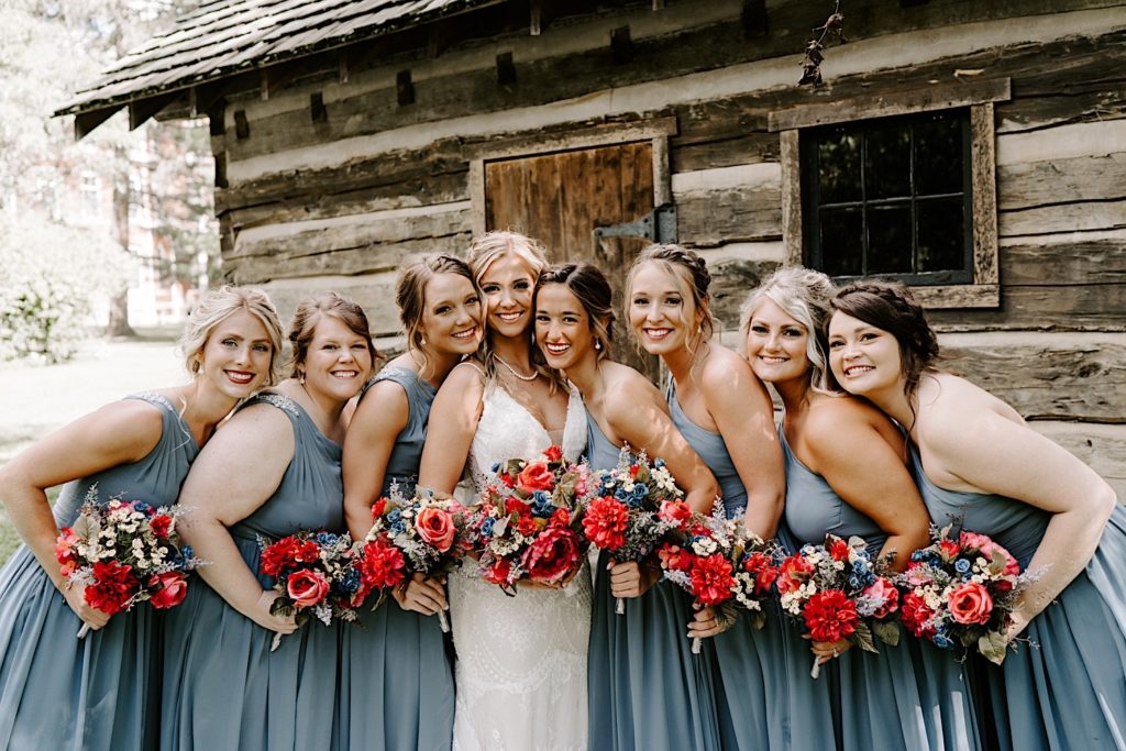 Bride surrounded by her bridal party in front of cabin