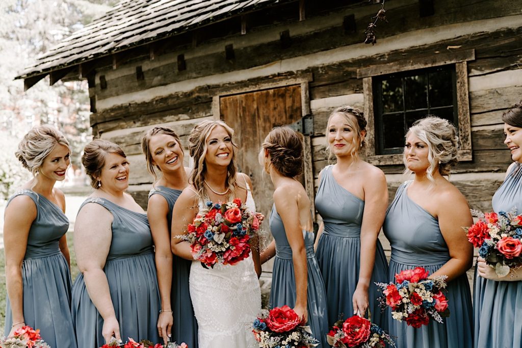 Bride surrounded by her bridal party in front of cabin