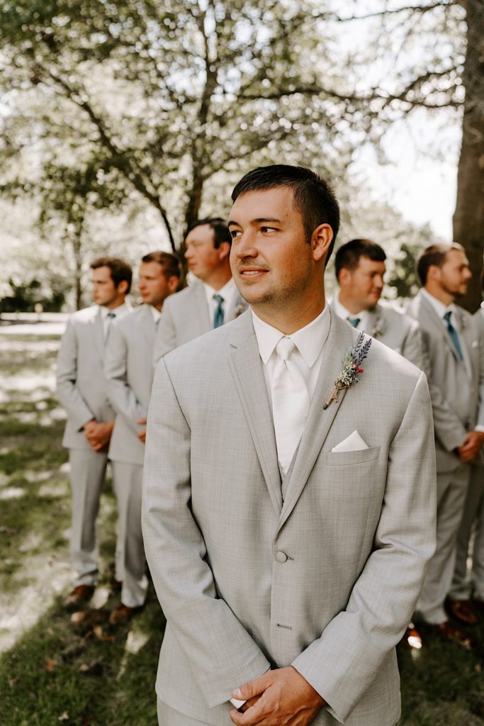Groom in forefront in front of his groomsmen in background