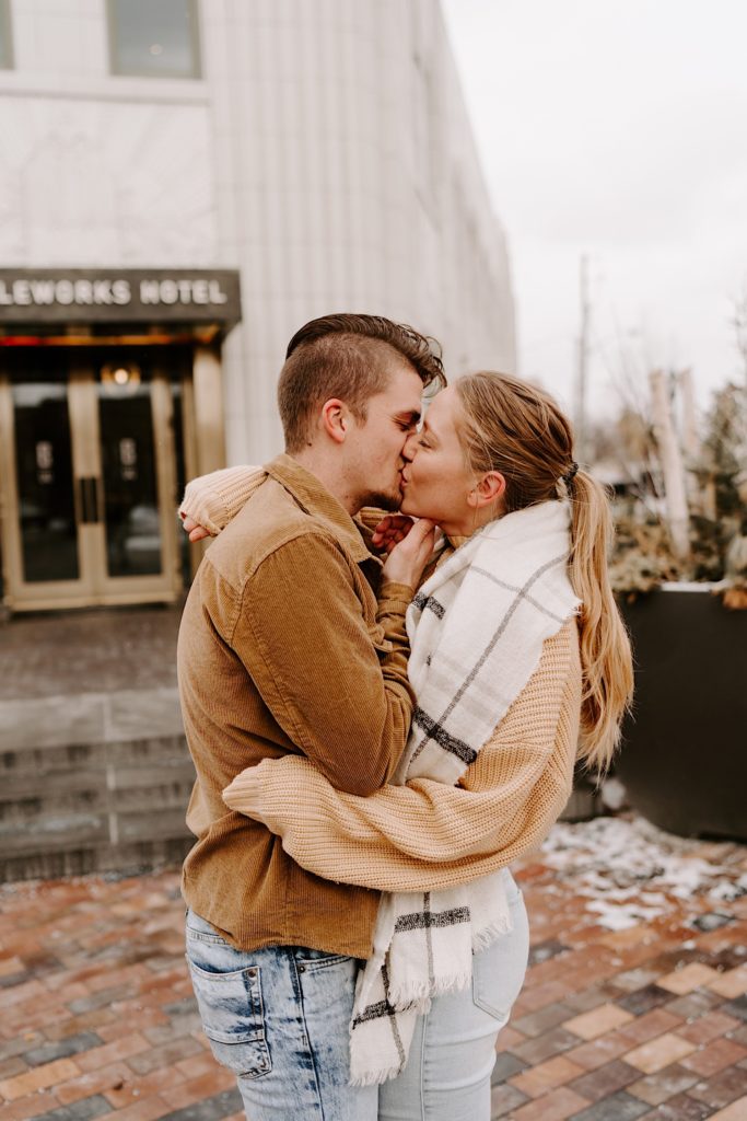 Couple kiss each other in front of a hotel during the winter