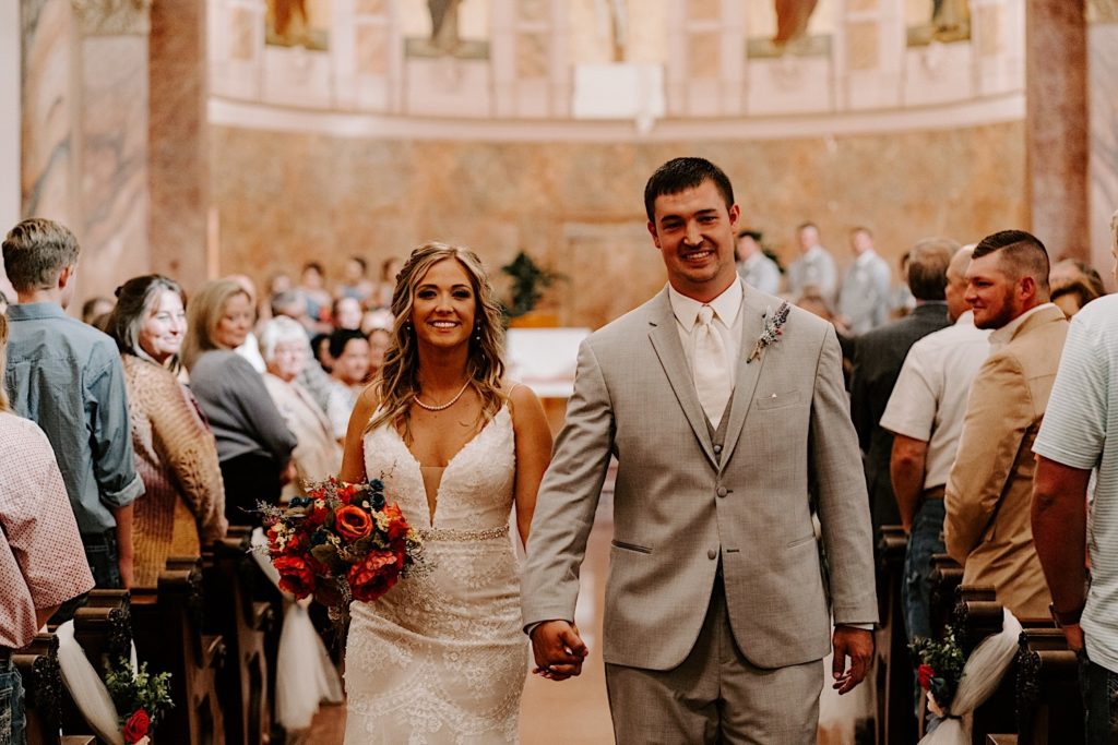 Bride and groom walking down aisle after ceremony in ornate Indiana church