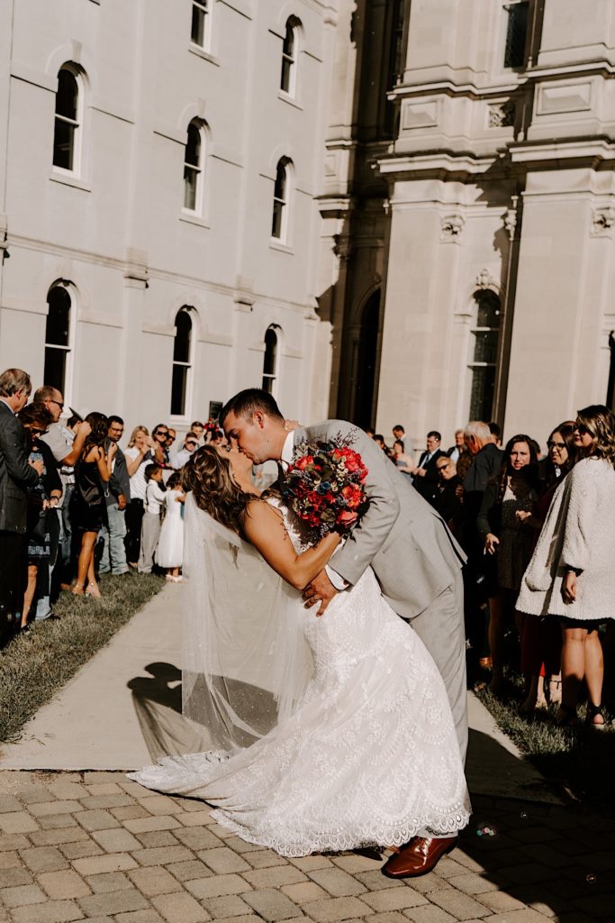 Bride and groom kissing in front of church after ceremony 