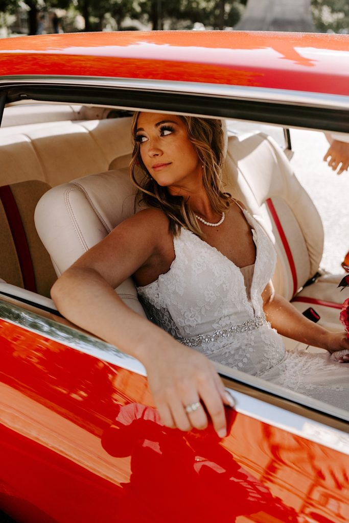 Bride sitting in passenger seat of red car