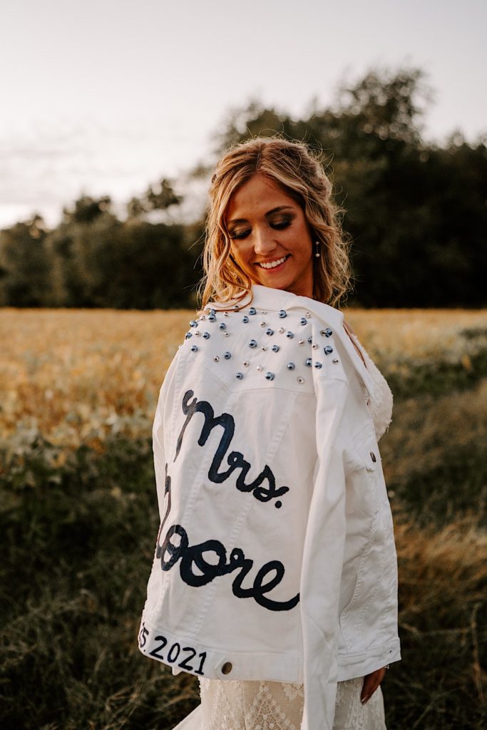 Bride looking back at white jacket with her new last name written on it