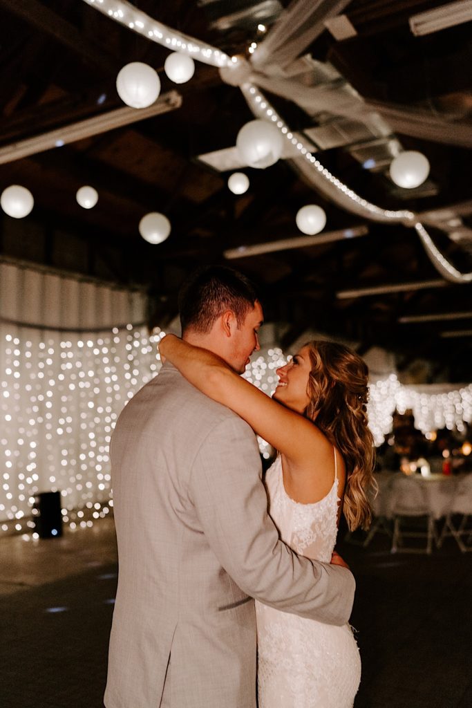 Newlyweds sharing first dance surrounded by string lights and lanterns