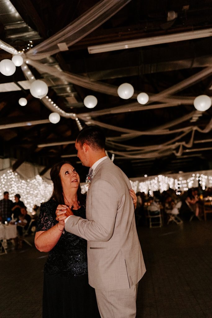Grooms first dance with mother in Indiana wedding surrounded by lanterns and string lights