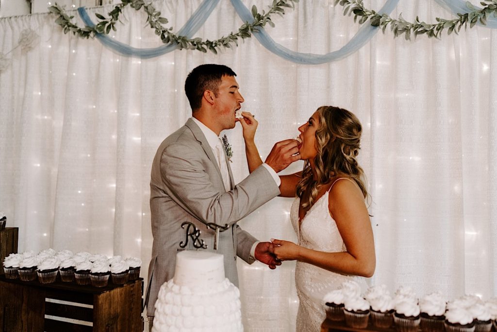 Bride and groom feeding each other cake in Indiana wedding reception