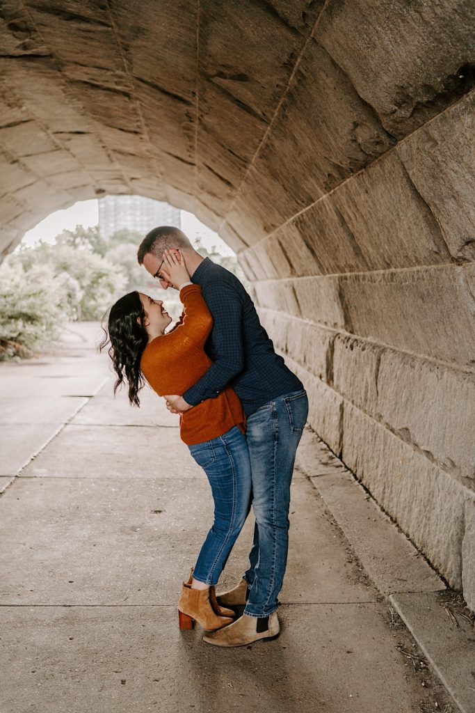 Couple embrace and look at one another underneath an overpass in Chicago's Lincoln Park