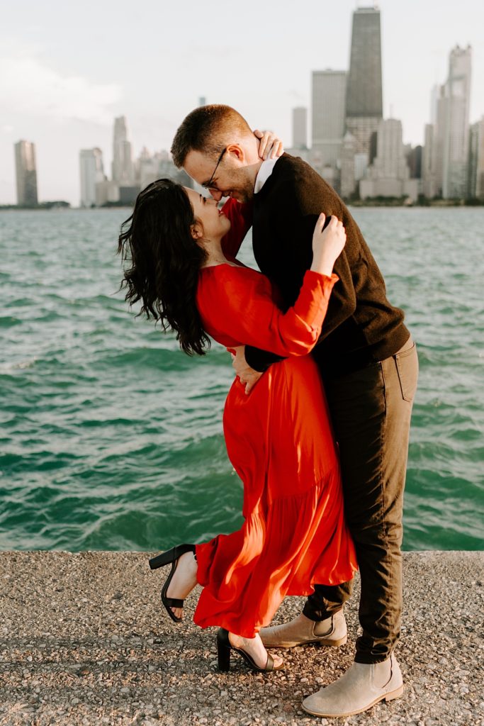 Couple embrace and smile at one another at North Avenue Beach in front of Lake Michigan and the Chicago skyline