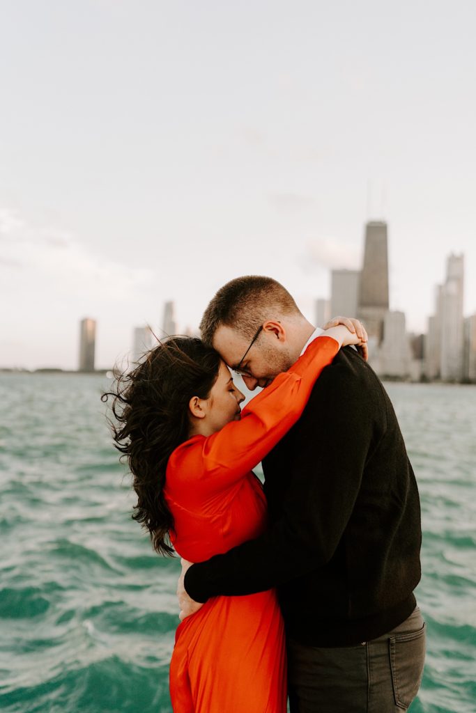 Couple embrace and touch their foreheads together at North Avenue Beach in front of Lake Michigan and the Chicago skyline
