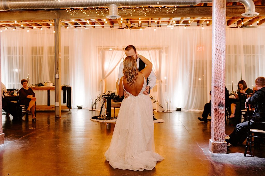 Newly weds share first dance together at their receptions space while their guests watch