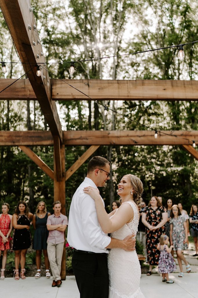 Newly weds share first dance together while surrounded by their guests at their outdoor reception space