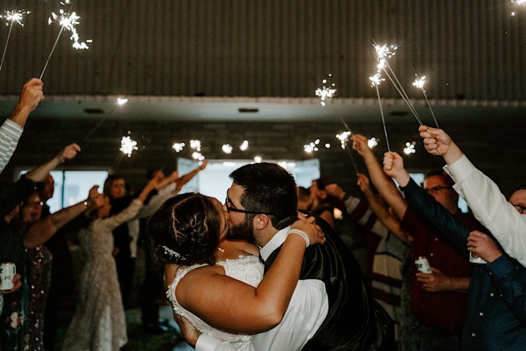 Newlyweds kissing surrounded by sparklers at Indiana wedding reception