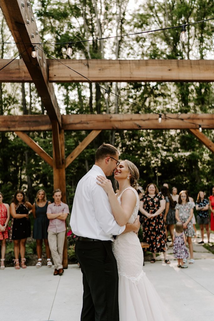 Newly weds share first dance together while surrounded by their guests at their outdoor reception space