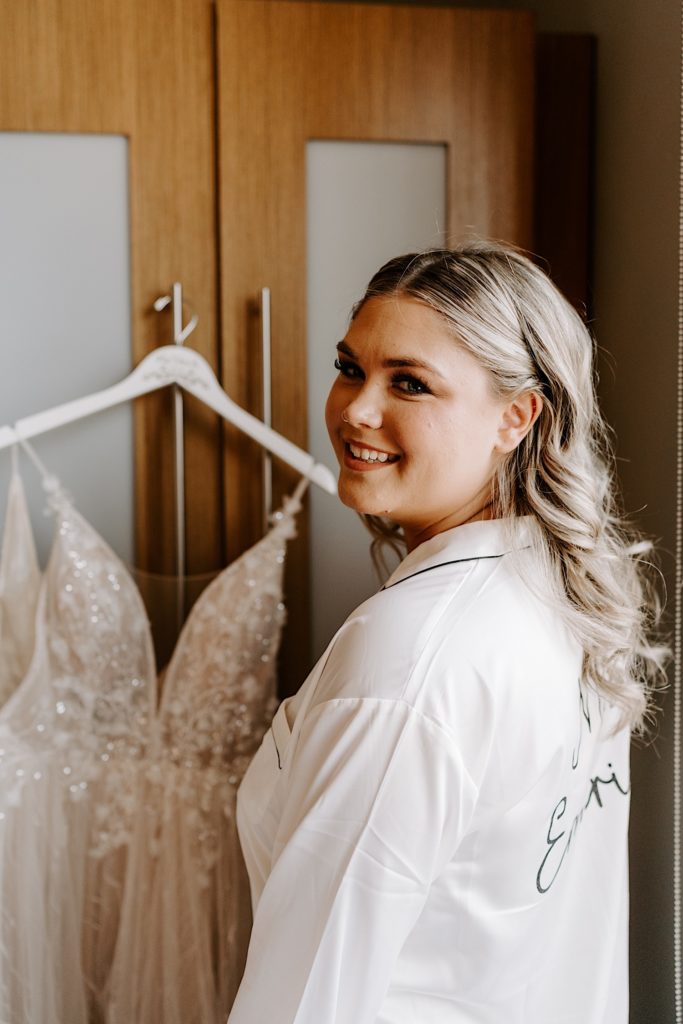 Bride smiling in front of hanging wedding dress