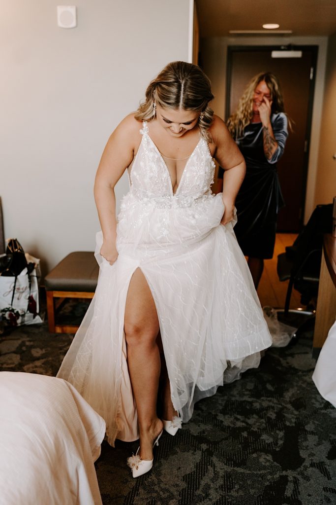 Bride putting her shoes on before ceremony with mother in background
