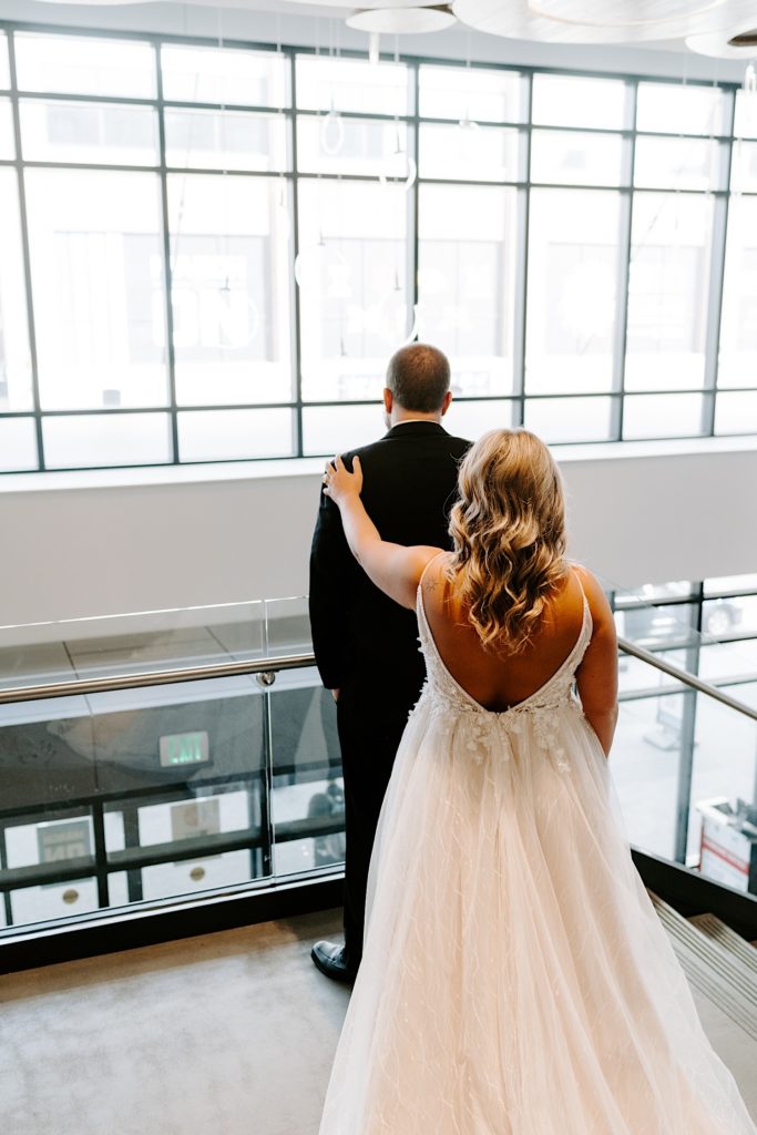 Bride touching grooms shoulder from behind prior to first look in downtown Indianapolis
