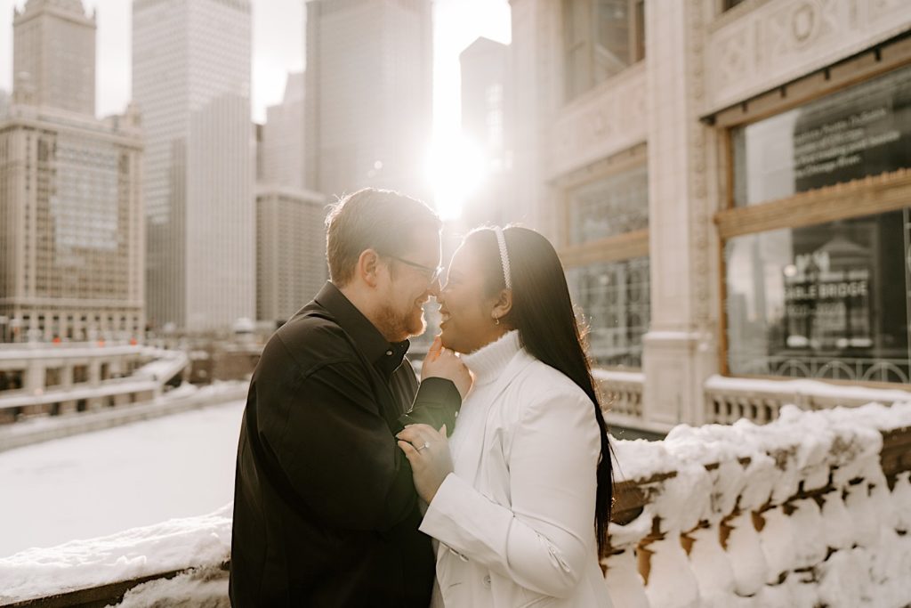 Engaged couple smiling at each other on snowy Chicago riverwalk