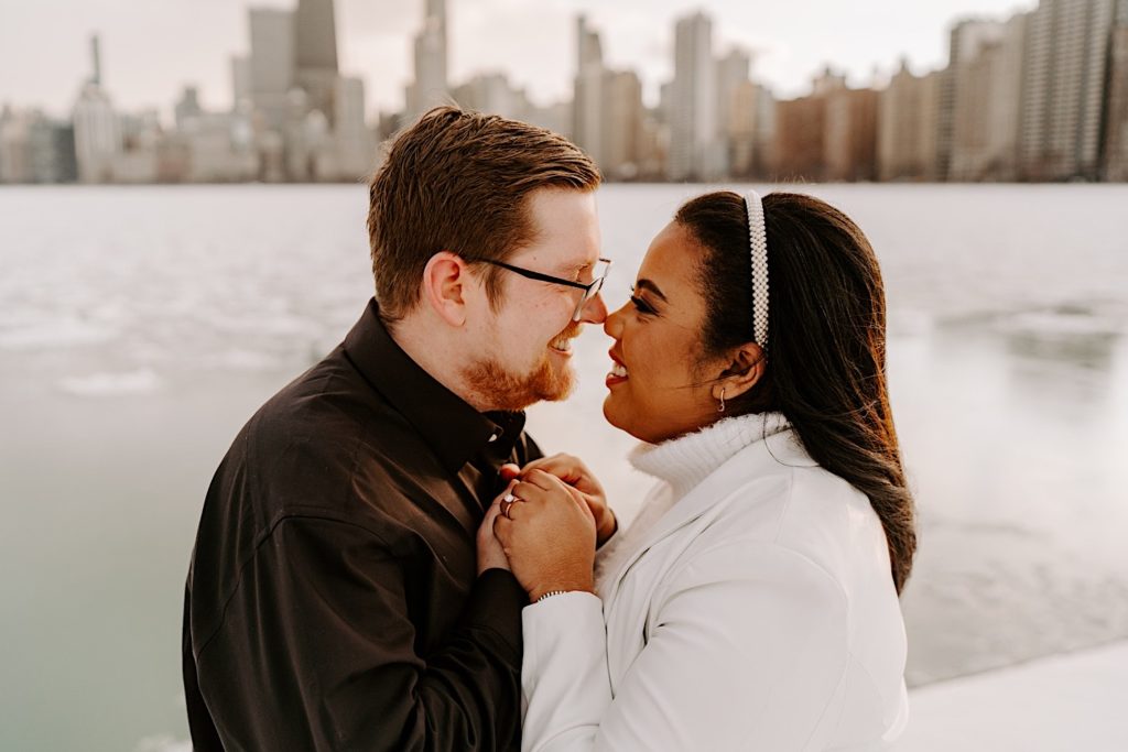 Engaged couple hugging on Chicago riverfront with skyline behind them