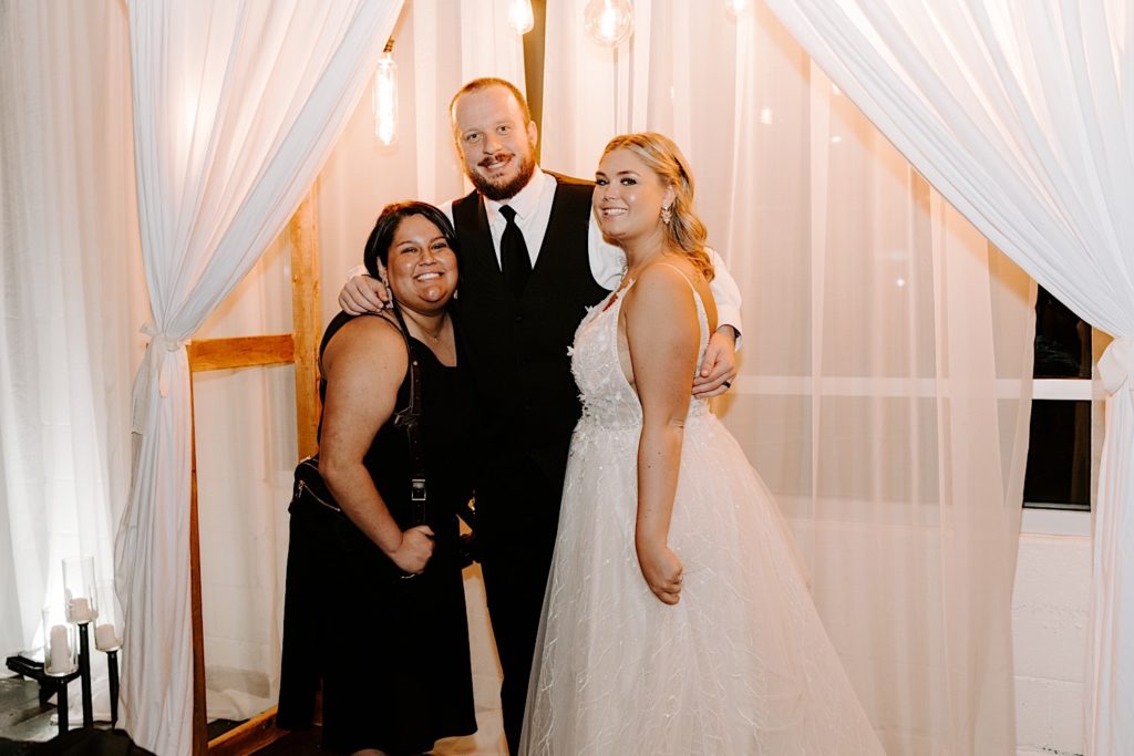 Newlyweds pose with wedding guest at Ivory Foundry wedding reception