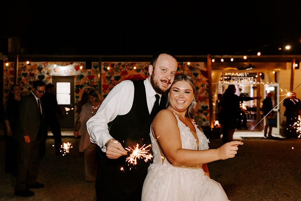 Newlyweds holding sparklers outside Ivory Foundry wedding reception