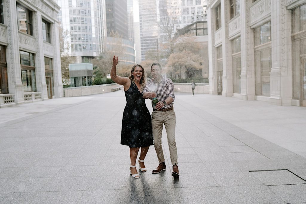 Engaged couple popping champaign in downtown Chicago engagement session