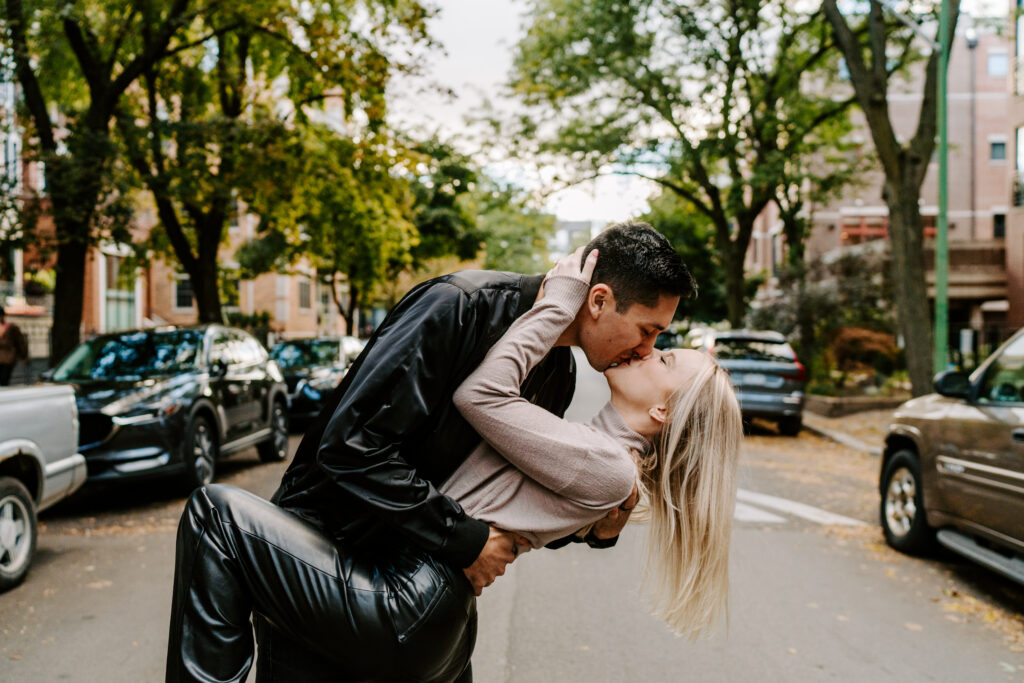 A couple kisses while walking through their neighborhood in Chicago during their engagement photos