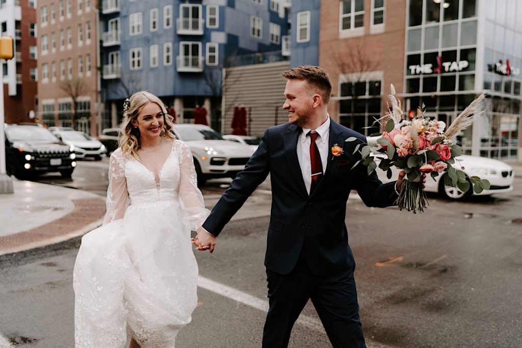 Bride and groom walk on the streets of Chicago while holding a pink bouquet.