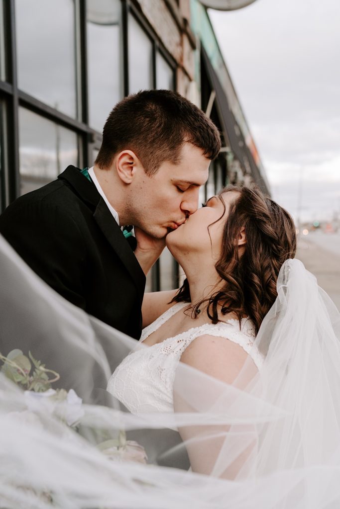 Bride and groom kiss while standing outside their Chicago wedding venue in Fulton Market.