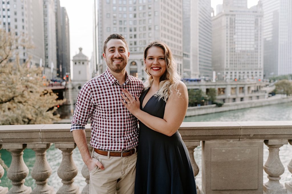Couple stands in front of Chicago Riverwalk smiling at the camera.