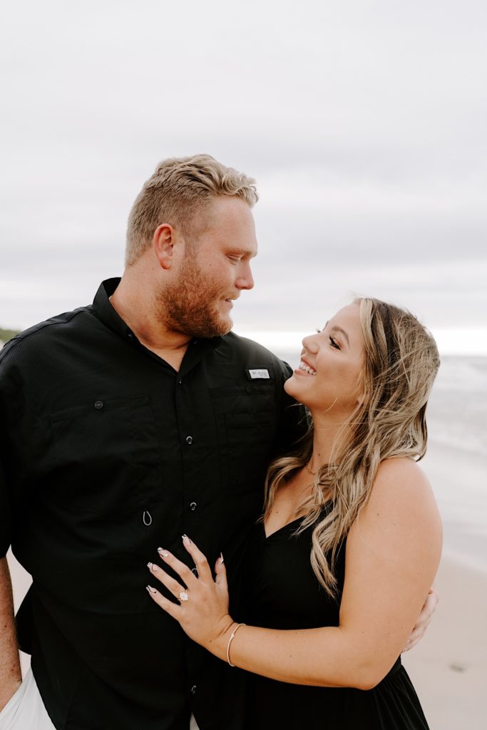 engaged couple takes engagement photos wearing a black button up and black maxi dress.