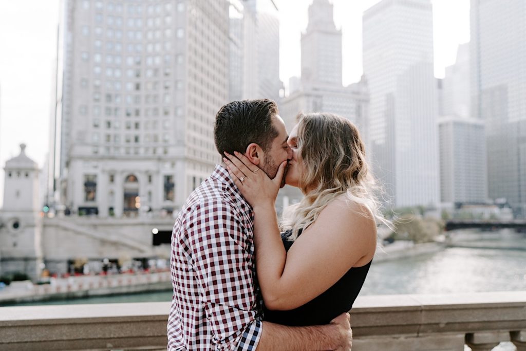 Couple kisses overlooking the Chicago Riverwalk during their engagement session.