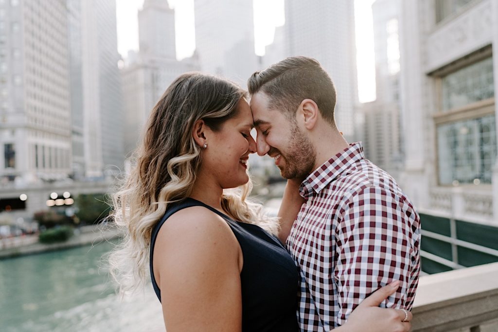 Couple presses their noses together while smiling while overlooking the Chicago River.