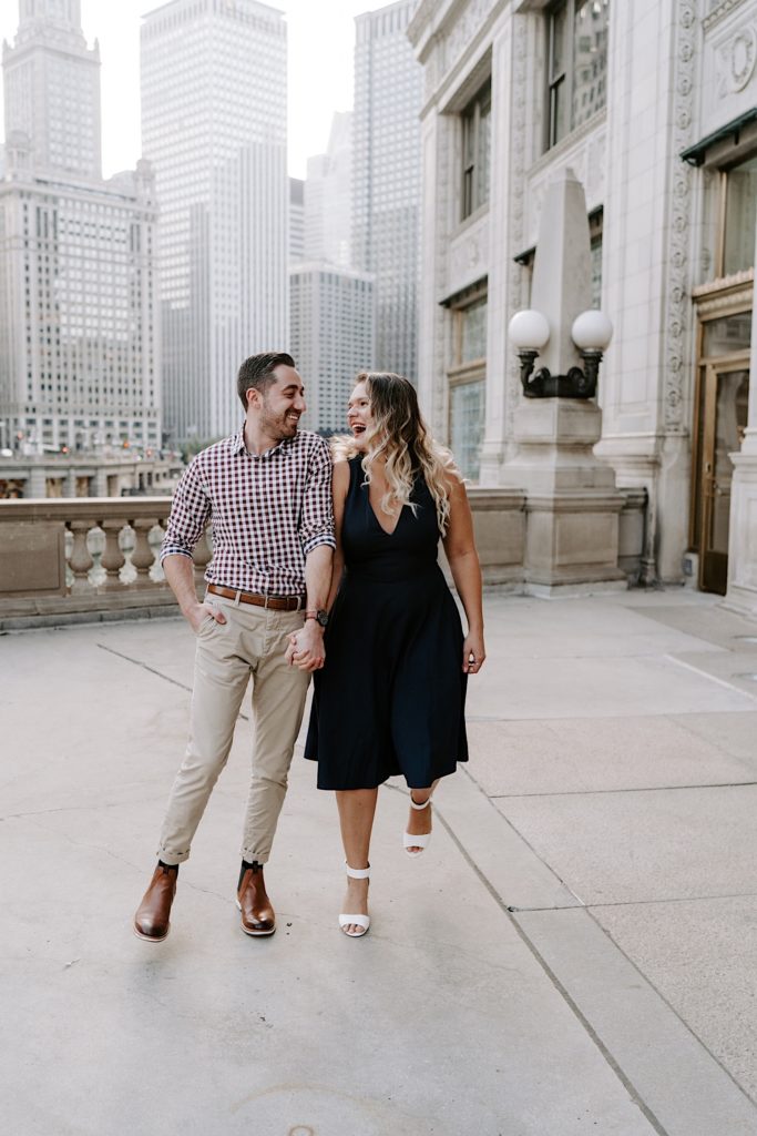 Couple walks towards the camera laughing and looking at each other in the loop in Chicago.