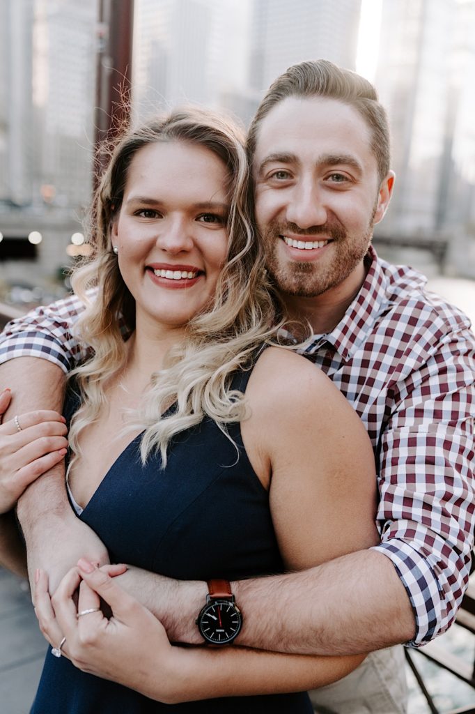 engaged couple smiling at the camera with their faces right next to each other in Chicago