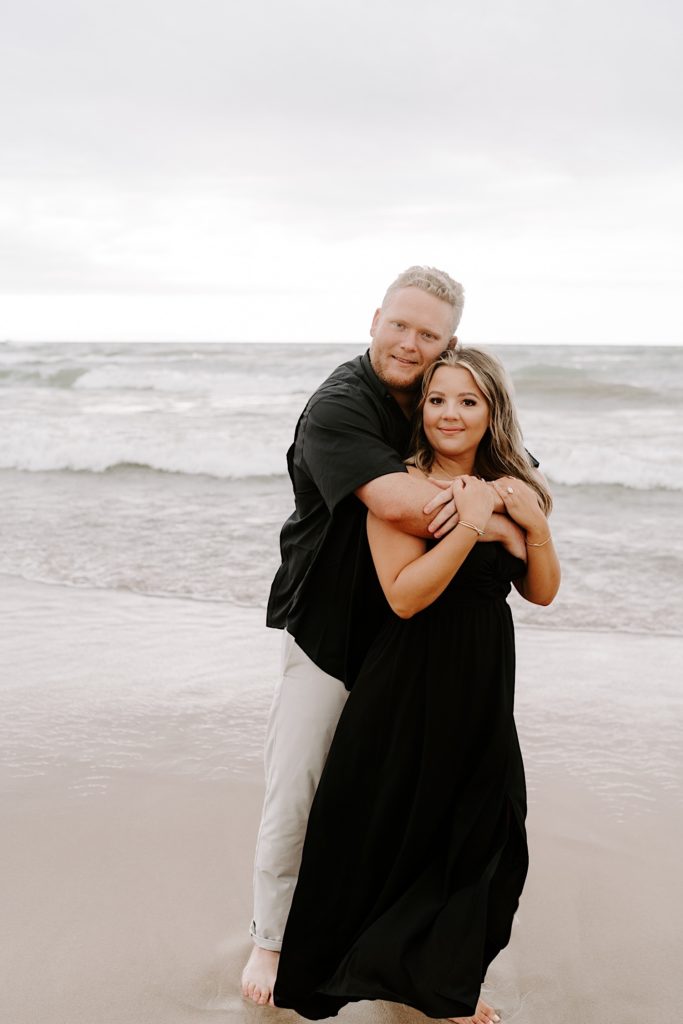 Bride and groom wear all black for their beach engagement session together.