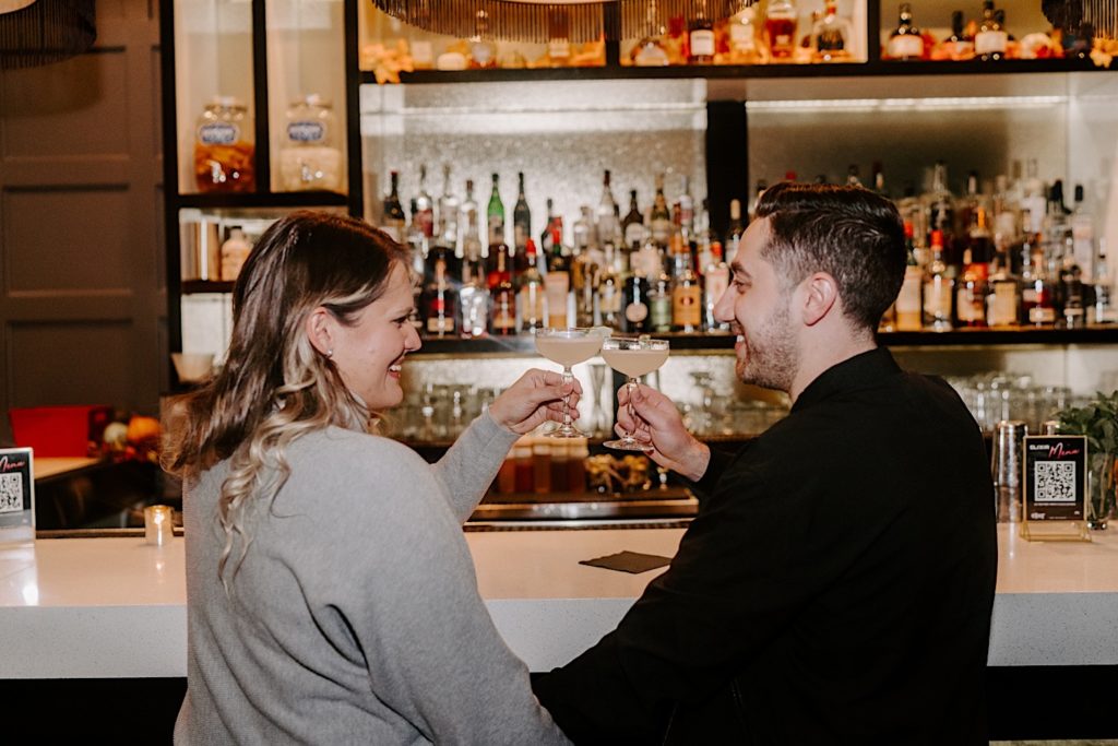Couple cheers while sitting at the bar Elixir during their Chicago engagement session