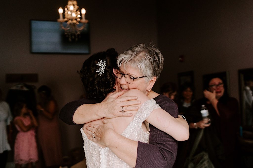 Bride embraces her mom on her wedding day in a strapless wedding dress.