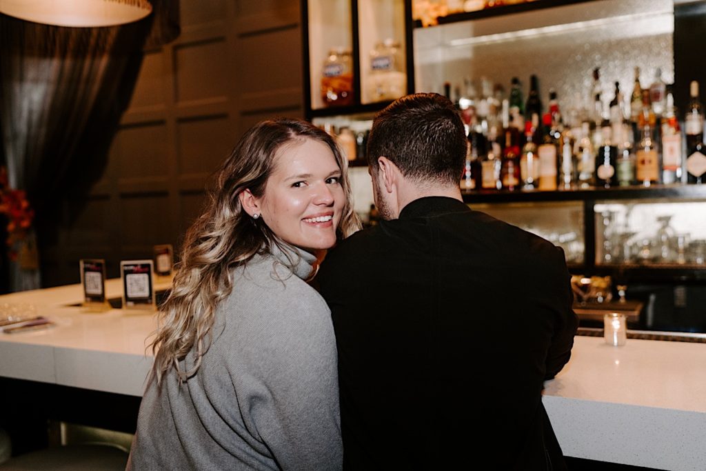 Fiance looks back at the camera while she sits with her soon to be husband at the bar Elixir Chicago