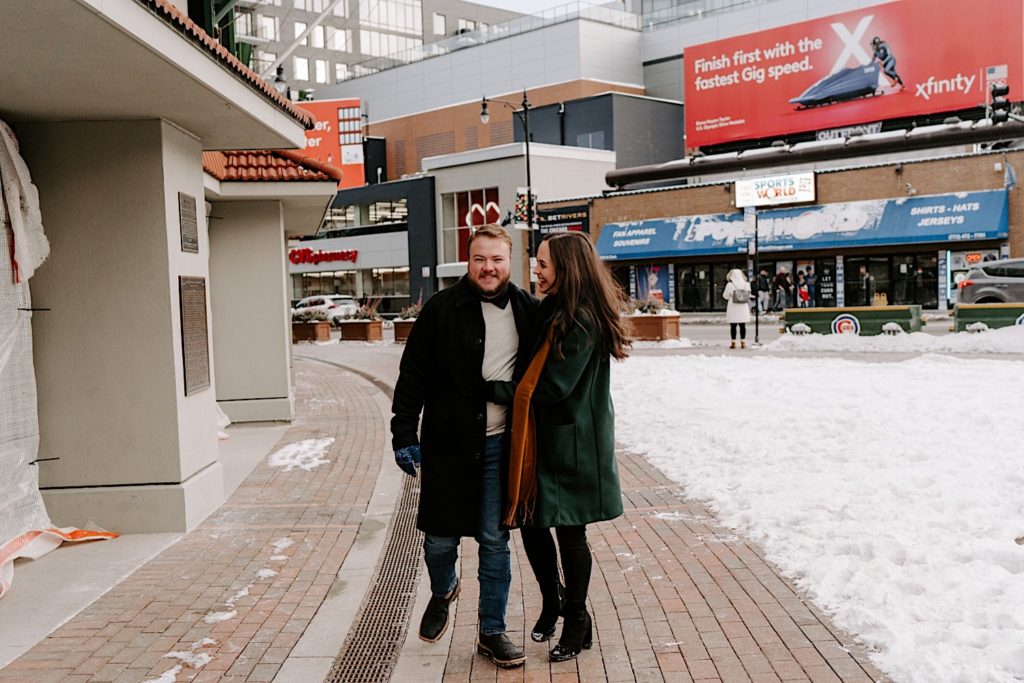 Couple takes winter engagement photos in Chicago while walking in Wrigleyville.
