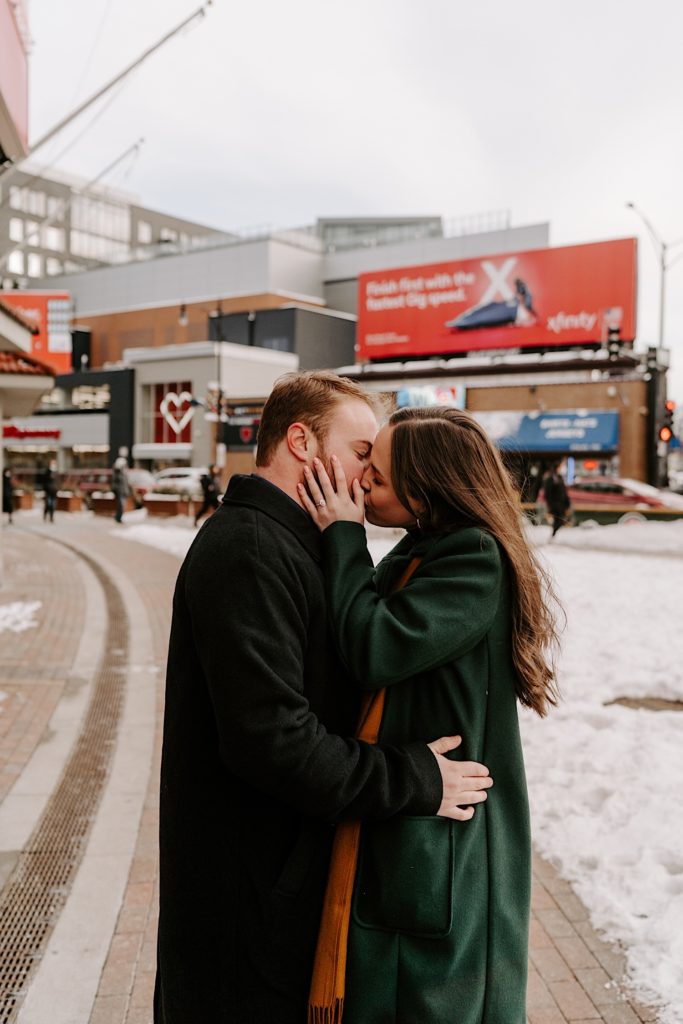 A couple in their winter gear kisses outside Wrigley Field for their winter engagement session.