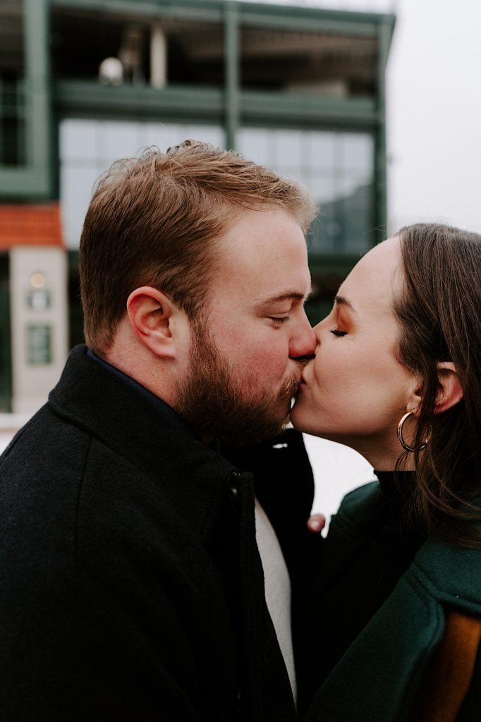Bride and groom kiss outside of Wrigley Field during their winter engagement session.