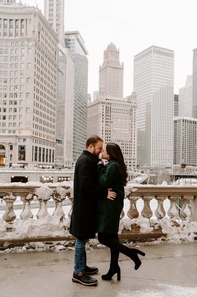 Couple snuggles in the winter in Chicago with Tribune Tower behind them.