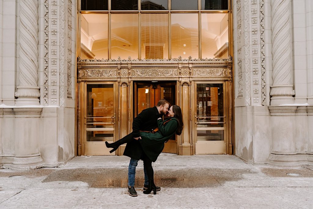Couple dips outside the gold entrance of the Tribune Tower during their winter engagement session.