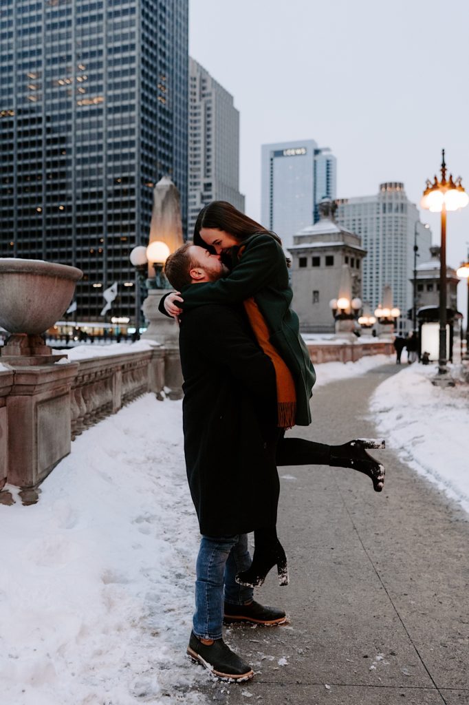 Engaged couple kisses on the Chicago riverwalk during their winter engagement session.