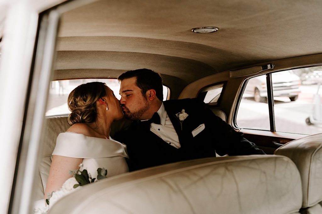 Bride and groom kiss in the back of a 56 Rolls Royce before their Indianapolis wedding