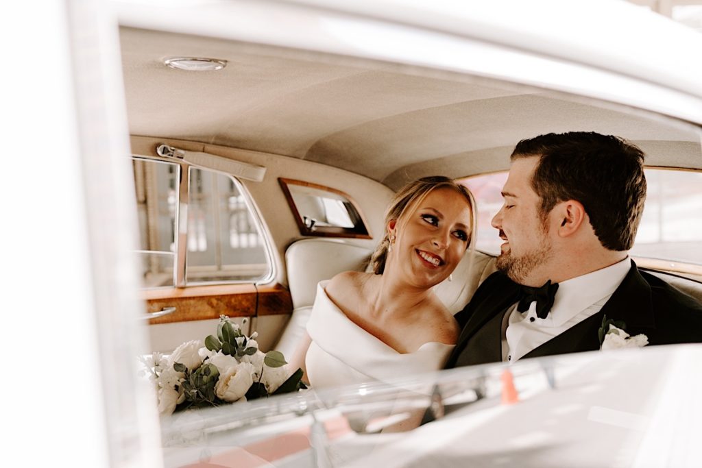 Bride and groom look at eachother in the back of a 56 Rolls Royce before their Indianapolis wedding